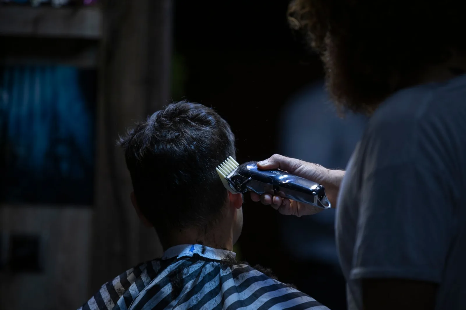 A barber uses electric clippers for a precise haircut in a barbershop.