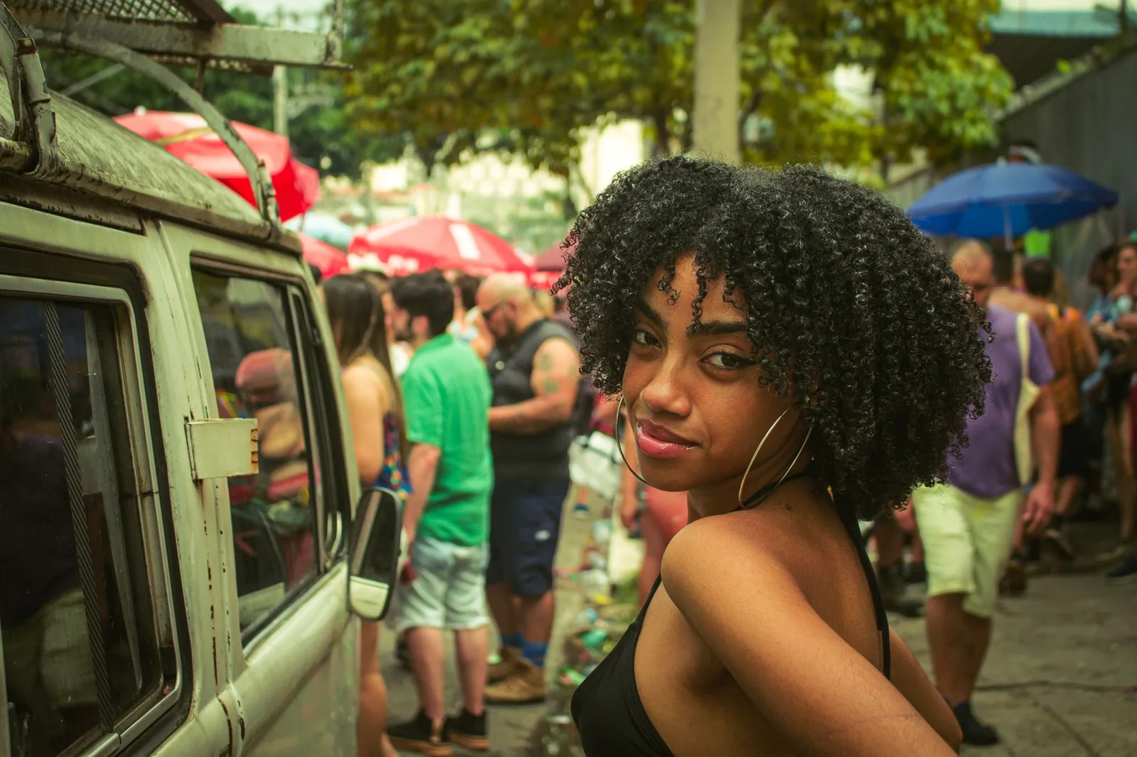 A Black woman with a full, healthy natural afro smiling on a sunny street.