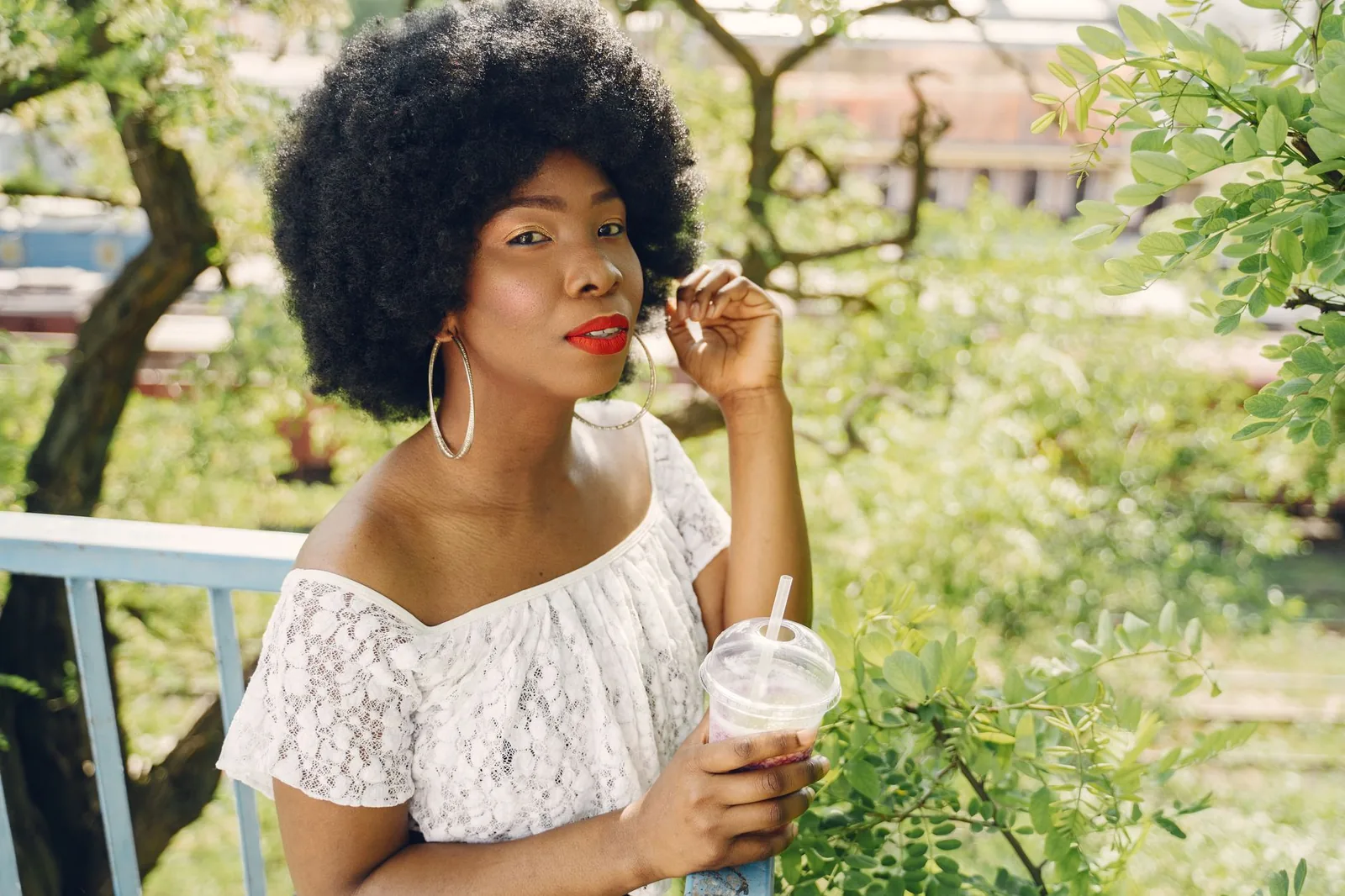 A Black woman with a full, healthy natural afro standing outdoors in the sun.