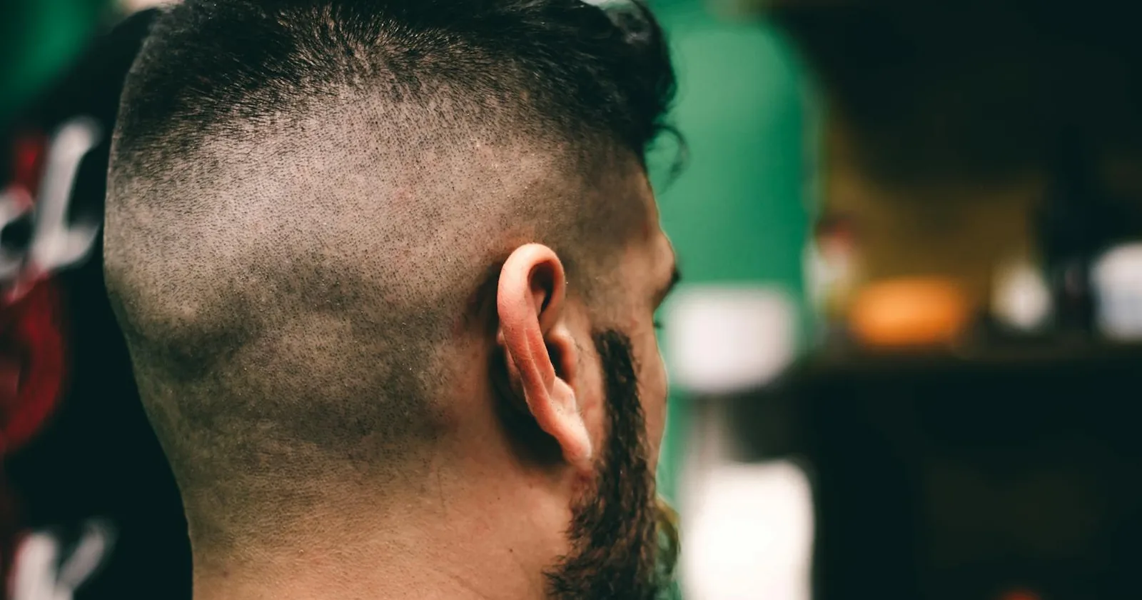 Rear view close-up of a man with a fresh sharp fade haircut at a barbershop.