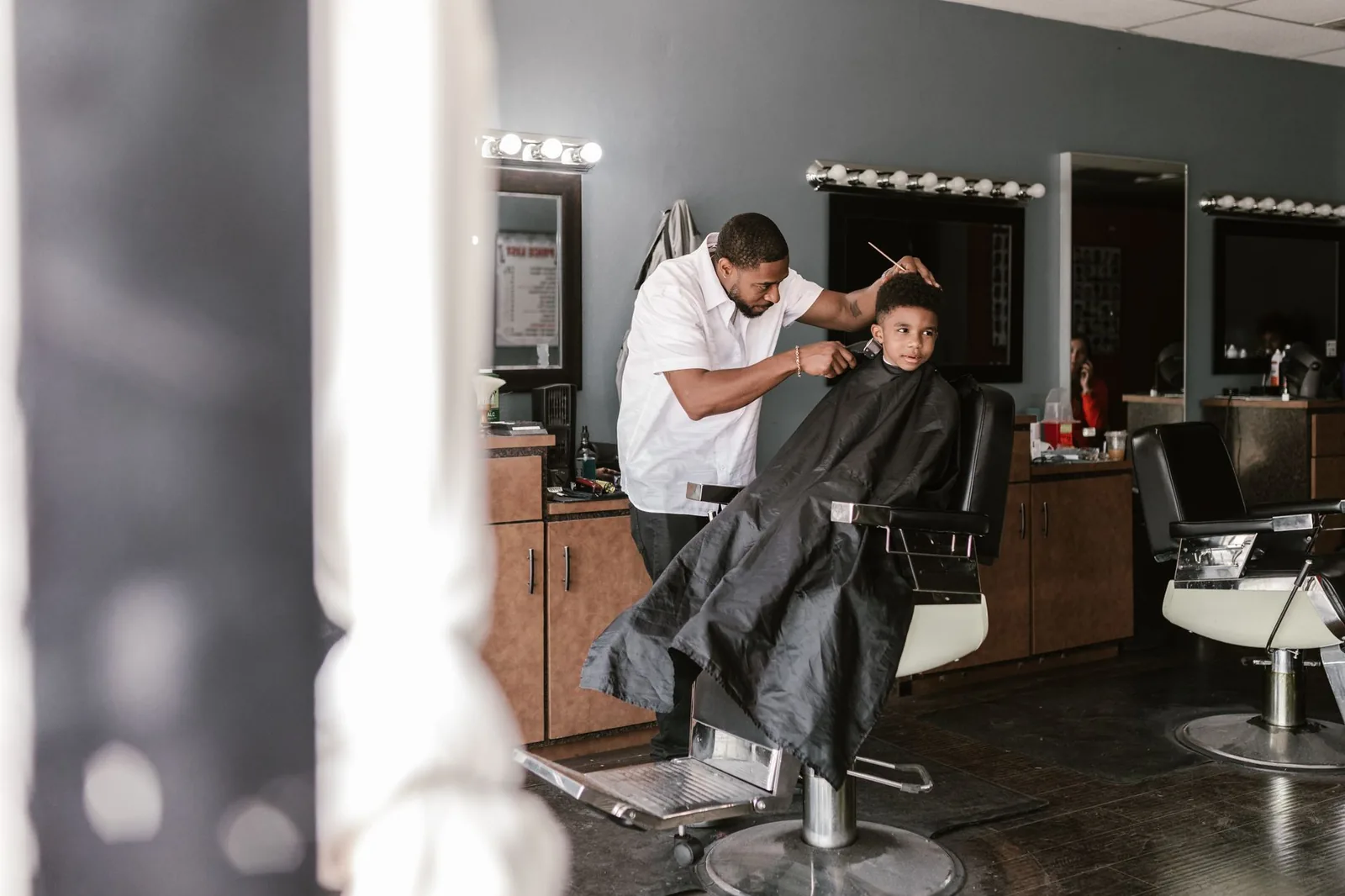 A barber cutting a young boy's hair in a barbershop