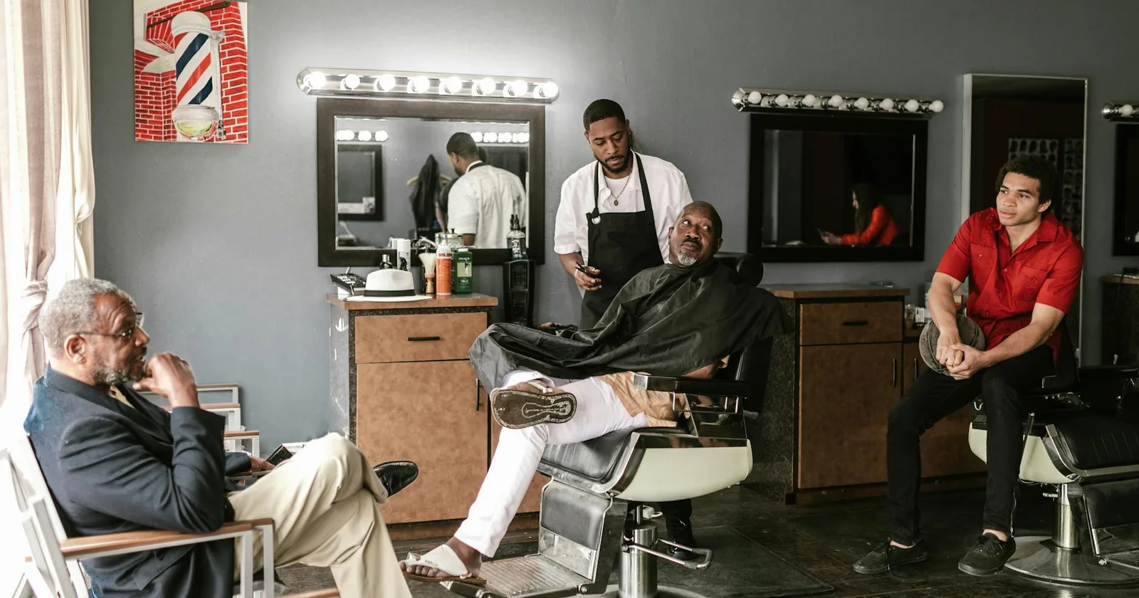 A stylish Black barber shop with clients and a barber in a relaxed, classic grooming setting.