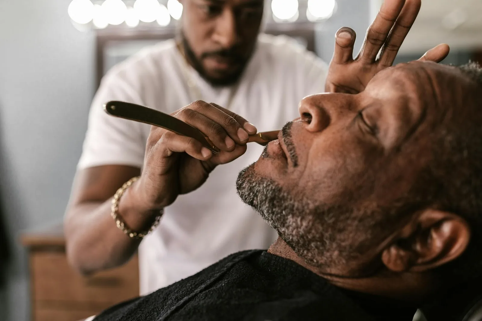 Close-up of a skilled barber using a straight razor for precise edge-up detailing.