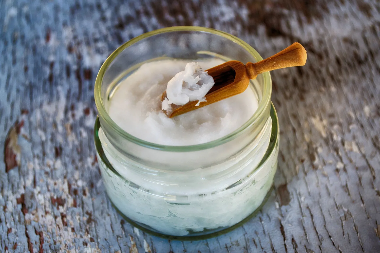 Coconut oil in a glass jar with a wooden scoop
