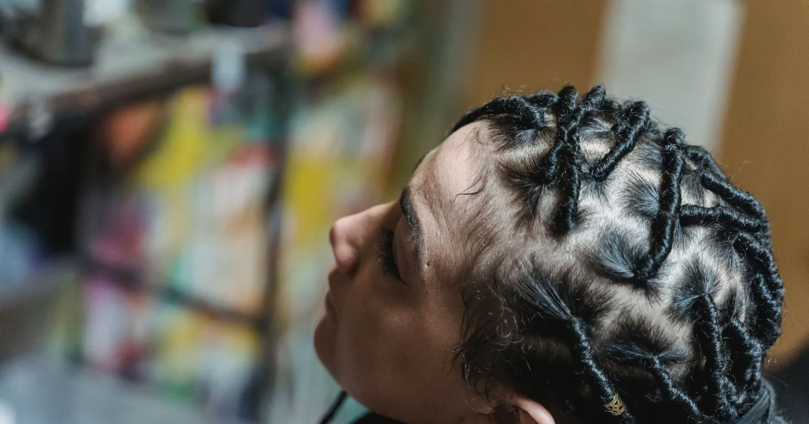 Detail of a Black woman's intricately braided hairstyle showing the texture and tension lines along the scalp.