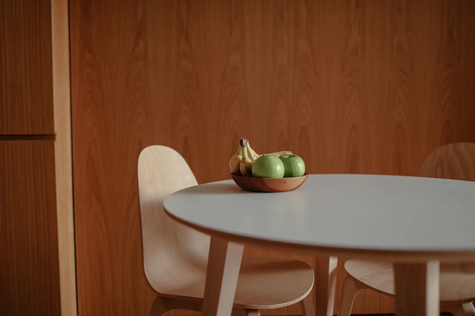 A bowl of bananas and green apples on a table
