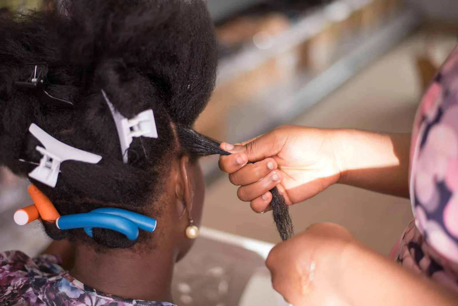 A hairdresser sectioning and styling a client's hair with clips in a salon.